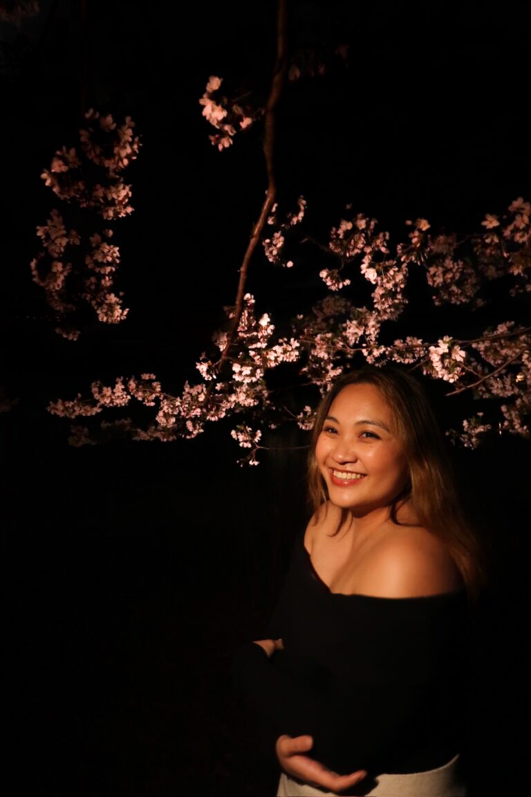 A night portrait session under cherry blossoms, framed against a city skyline.